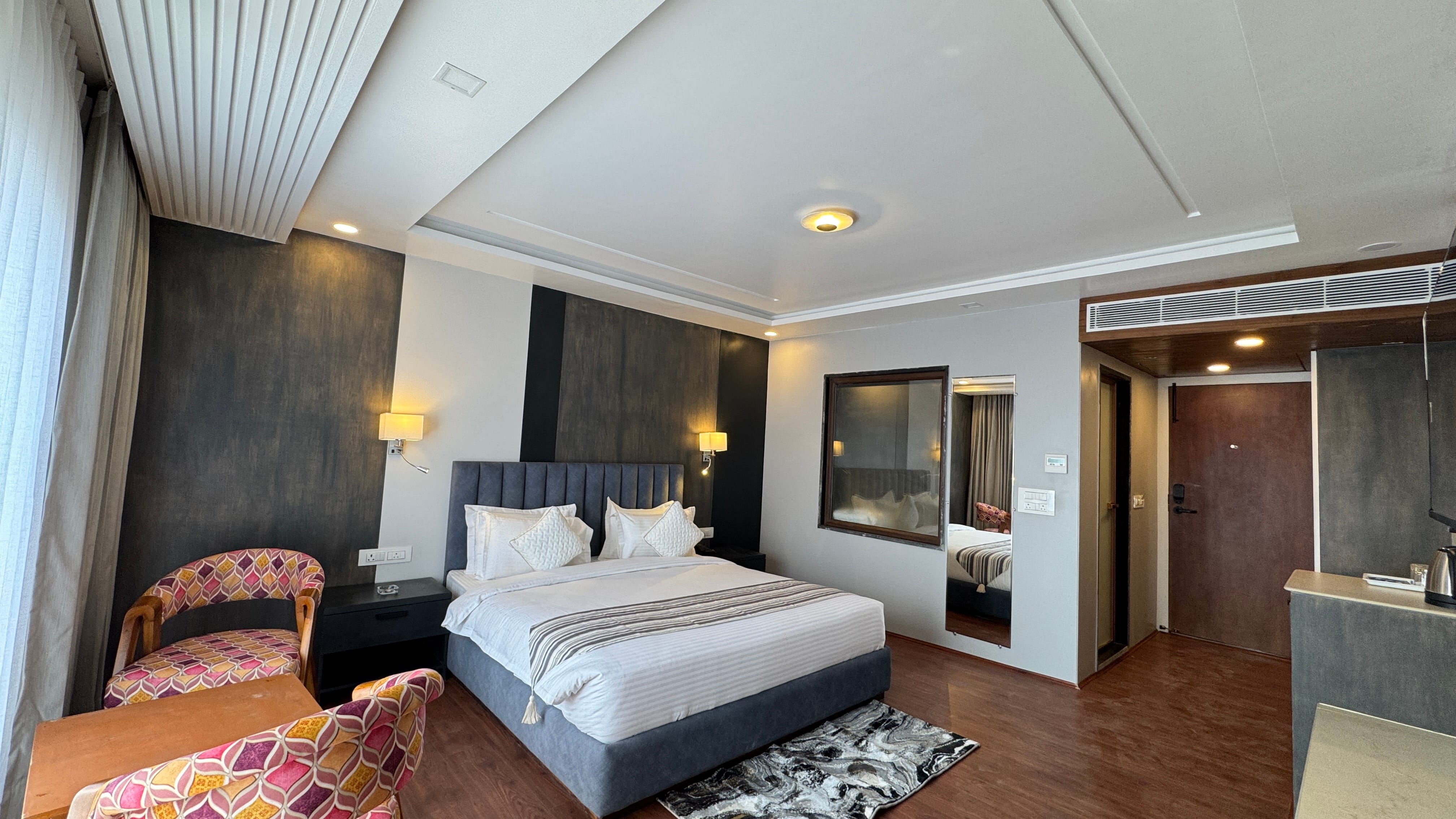 Wider angle view of elegant bedroom with blue headboard and sitting area
