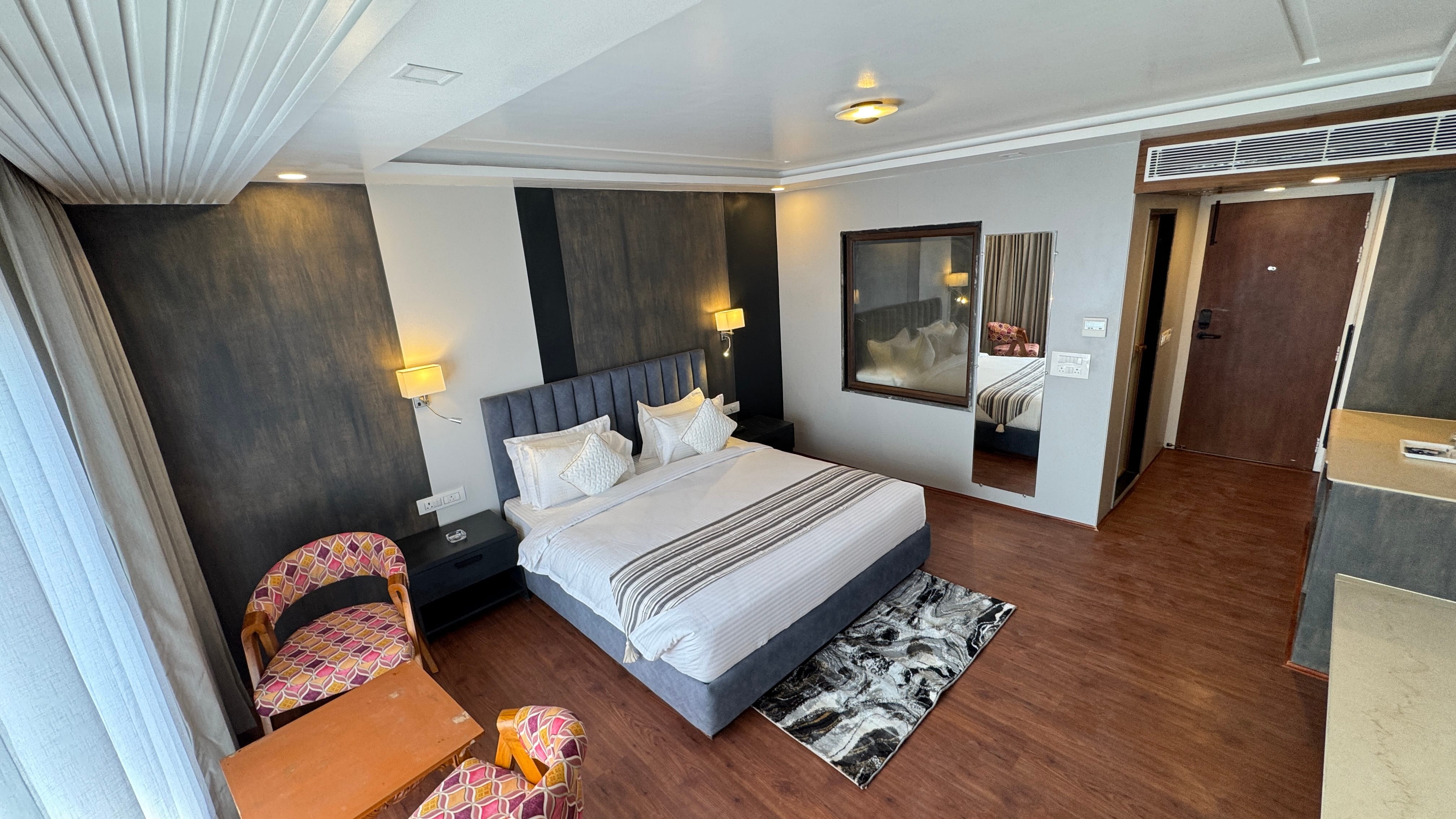 Spacious deluxe room with blue headboard, wider angle showing seating area