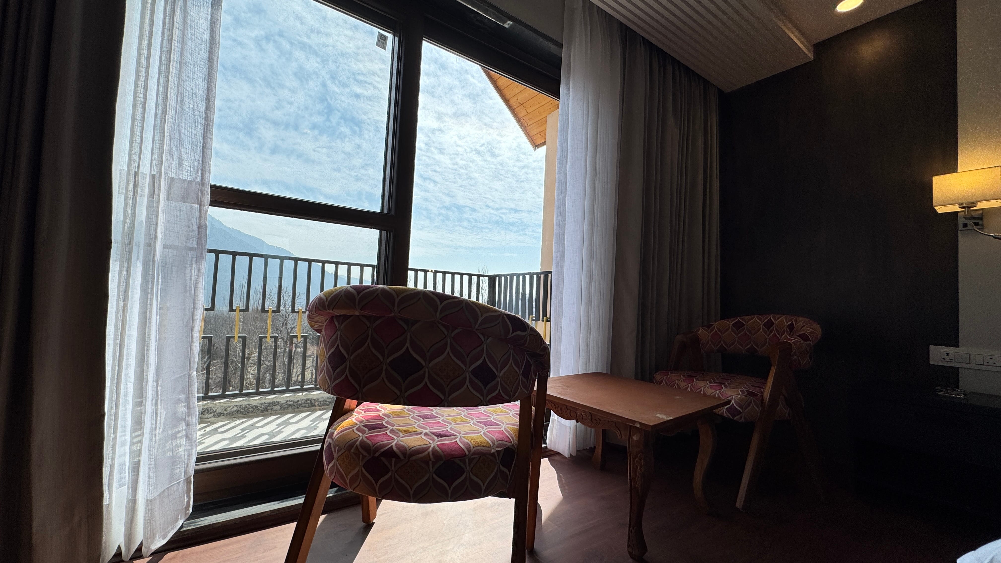 Private balcony with colorful chairs overlooking Pahalgam valley and mountains