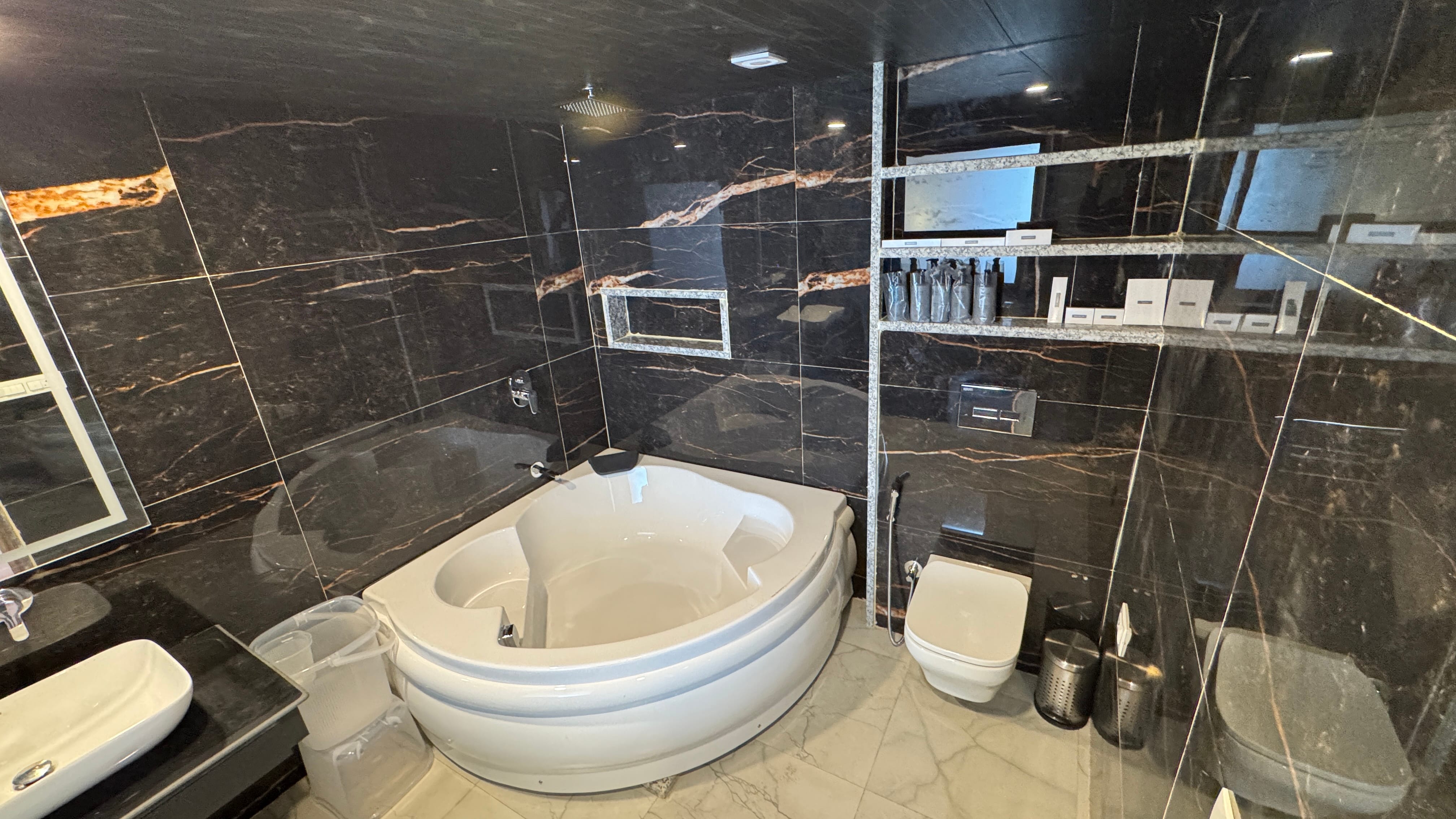 Jacuzzi bathroom with dark marble and corner tub