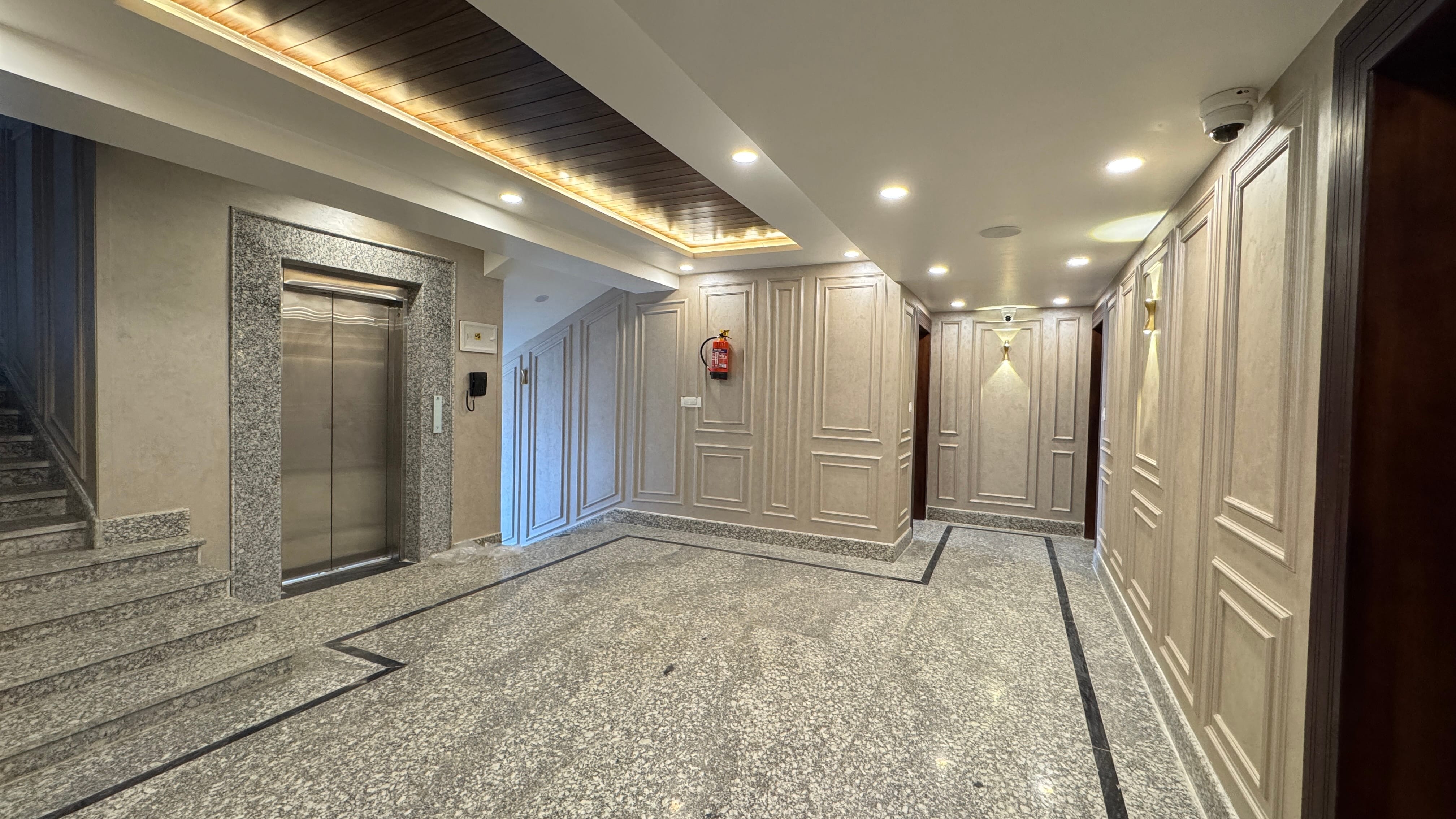 Hotel lobby with elevator entrance and elegant wood-paneled ceiling